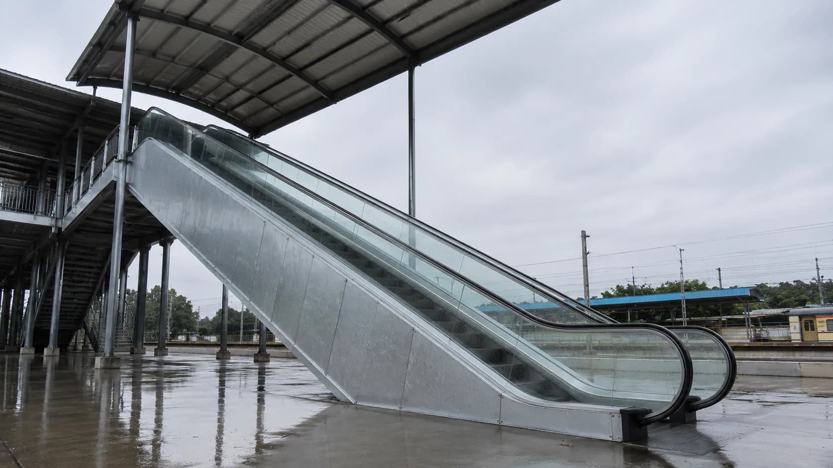 Outdoor heavy-duty escalator at a railway station, hot-dip galvanised truss under weather exposure
